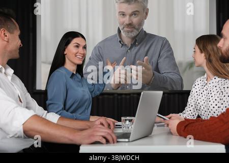 Gruppe von Personen, die an einer Geschäftskonferenz im Innenbereich teilnehmen. Lautsprecher auf Projektionsleinwand Stockfoto