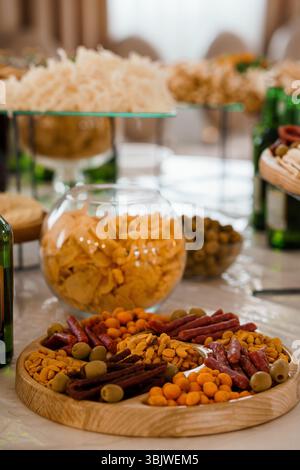 Eine üppig gestaltete Wurstplatte bietet eine Vielzahl an Snacks, darunter Brezeln, Oliven, Salami, Nüsse und Cracker, gestylt für Partys und Gat Stockfoto