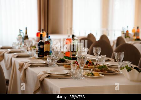 Ein wunderschön gestalteter Tisch für die Hochzeitsfeier ist mit feinem porzellan, Besteck, Weingläsern und Vorspeisen ausgestattet. Eine beige und cremefarbene Farbpalette schafft das Stockfoto