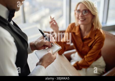 Kaukasische junge Erwachsene Frau lächelt, während sie beim Kellner im Restaurant Essen bestellt Stockfoto