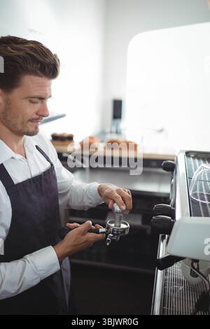 Männlicher Barista mit Portafilter und Topping Espresso am Kaffeeschalter, Kopierraum Stockfoto