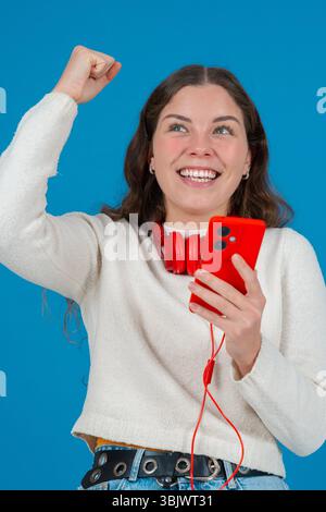 Vertikales Porträt begeisterte junge Frau, die beim Anschauen des Smartphones feierte Stockfoto
