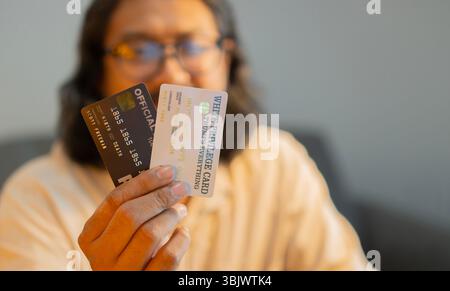Selektiver Fokus des fröhlichen Mannes mit Kreditkarten mit Handy zur Hand im Wohnzimmer zu Hause. Online-Shopping mit Kreditkartenkonzept. Stockfoto