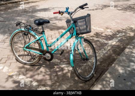 Gili, Lombok, Indonesien - 3. Januar 2025: Blaues Fahrrad mit Korb auf der Vorderseite. Der Korb ist leer. Das Fahrrad steht am Straßenrand Stockfoto