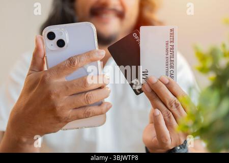 Zahlungen im digitalen Bereich. Nahaufnahme eines gutaussehenden glücklichen Mannes, der zu Hause ein Handy und Kreditkarten benutzt. Stockfoto