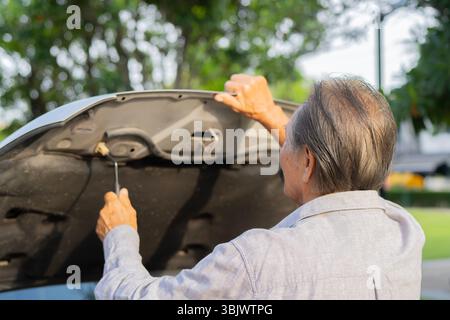Rückansicht eines älteren Mannes, der die Motorhaube öffnet, um den Motor im Freien zu prüfen und zu reparieren. Senior Skill-Konzept. Stockfoto