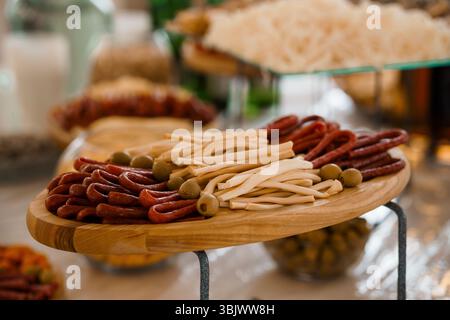 Eine lebendige Nahaufnahme zeigt eine wunderschön angeordnete Wurstplatte voller Wurstwaren, Käsestäbchen, Oliven und knusprigen Brotstäbchen Stockfoto