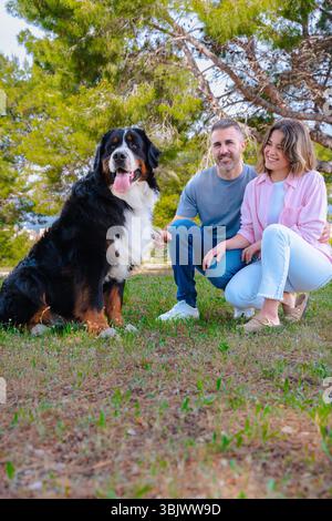 Kaukasisches Paar mit Hund, der draußen posiert und während des Urlaubs am Strand lächelt Stockfoto