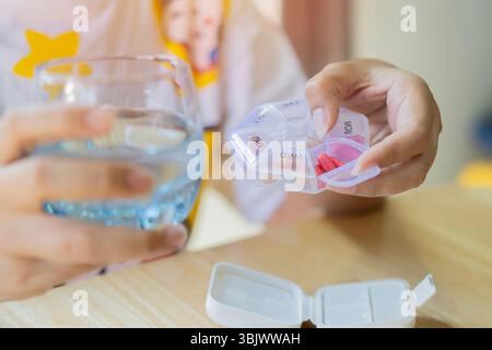 Nahaufnahme einer Hand, die eine kleine Kiste mit bunten Pillen und Kapseln hält. Pillen-Organisator-Konzept. Selektiver Fokus. Stockfoto