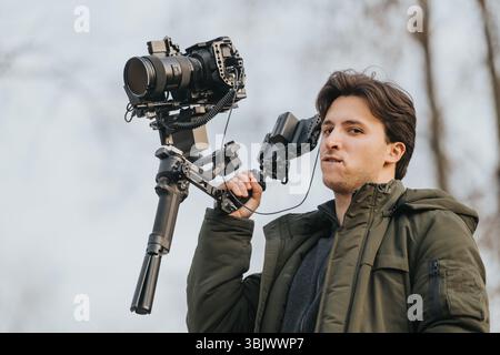 Mann, der während eines Videoshootages im Freien eine professionelle Kamera mit Stabilisator bedient Stockfoto