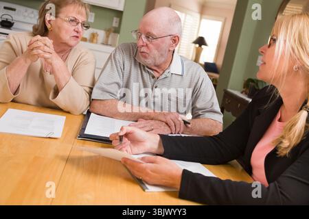 Ein älteres erwachsenes Paar, das mit Agent in ihrem Haus Papiere durchsucht Stockfoto