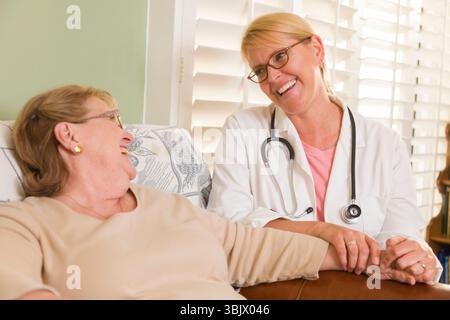Arzt oder Krankenschwester, die mit einer sitzenden Seniorin sprechen Stockfoto