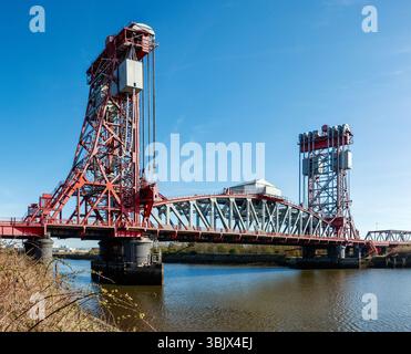 Die Red Tees Newport Bridge ist eine vertikale Brücke über einen ruhigen Fluss mit klarem blauen Himmel, die komplexe technische Konstruktion von middlesbrough zeigt Stockfoto