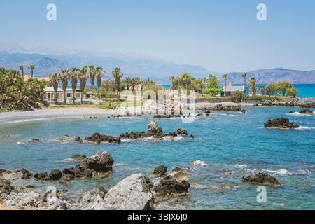Gemütliches exotisches kretisches Haus am Meer umgeben von griechischen hohen Palmen, mediterrane Landschaft Stockfoto