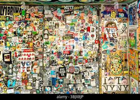 Eine lebendige Wand mit einer eklektischen Mischung aus Stickern und Street Art zeigt urbane Kultur und vielfältige künstlerische Ausdrucksformen in manhattan New york Stockfoto