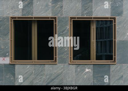 Zwei Aluminiumfenster an einer Steinmauer, Symmetrie Stockfoto
