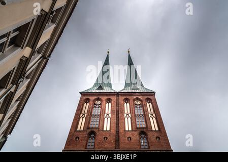 Flacher Blick auf die Türme der Nikolaikirche gegen den Himmel. Bewölkter Sommertag in Berlin Stockfoto