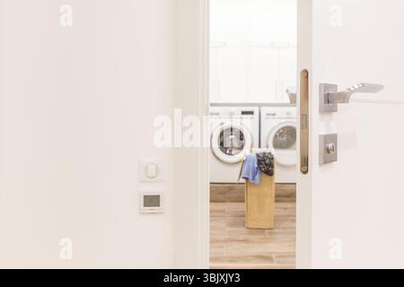 Blick durch die Tür zum Waschraum mit Korb und Waschmaschine Stockfoto