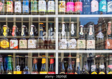 Gent, Belgien - 21. Mai 2025: Verschiedene Marken belgischer Bierflaschen und -Gläser in einem Schaufenster eines Spirituosengeschäfts in Gent, Belgien Stockfoto