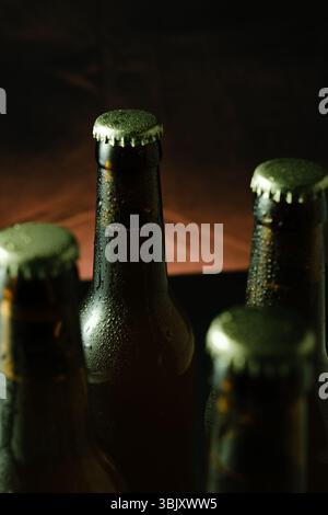 Nahaufnahme gekühlter Bierflaschen mit Kondensation bei dunkler stimmungsvoller Beleuchtung. Stockfoto