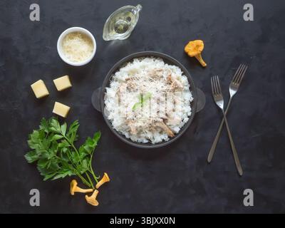 Risotto der Pfifferlinge in einer gusseisernen Pfanne auf einem schwarzen Tisch. Stockfoto