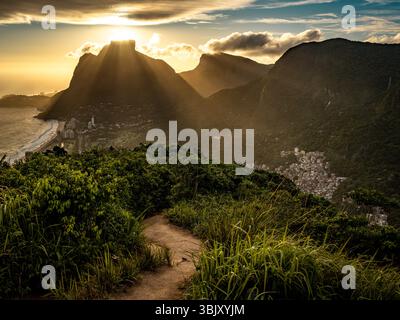 Goldener Sonnenuntergang Über Rio De Janeiro Vom Two Brothers Mountain: Dramatische Sonnenstrahlen, Die Durch Die Küstenspitzen Über Dem Atlantik Und Leblon Be Strömen Stockfoto