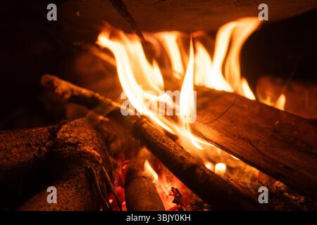 Eine Nahaufnahme von hellen Flammen, die nachts am Lagerfeuer Holz verbrennen. Stockfoto