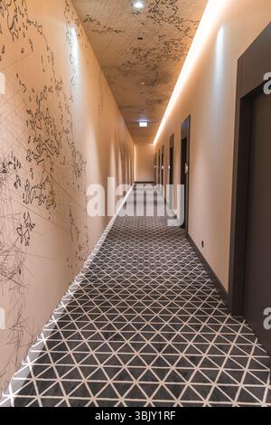 Moderner Hotelkorridor mit geometrischem Teppich und Leinenkunstwänden Stockfoto