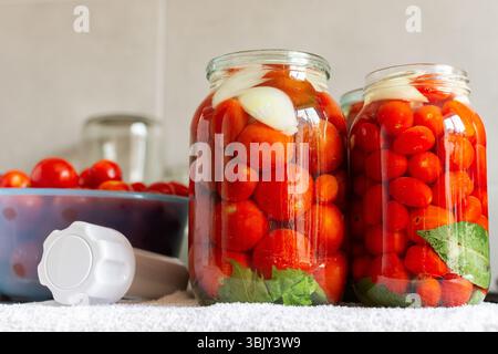 Hausgemachte Tomatenkonserven und Tomatensaft, konserviert und versiegelt für die Winterlagerung, Geschmack und Frische erhalten, Küchentisch mit vorbereiteten Tomatengläsern Stockfoto