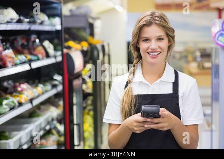 Weibliche Verkäuferin scannt Produkte im Regal mit Handscanner im Produktionsbereich, Kopierraum Stockfoto