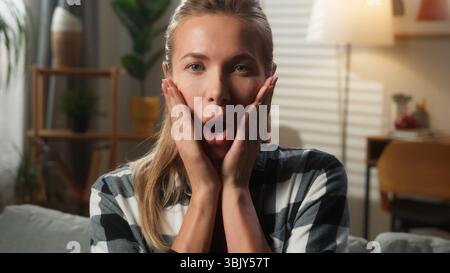 Schockierte kaukasische Frau europäische Frau, die in die Kamera im Wohnzimmer Home Porträt Mädchen Dame blickt unglaubliche erstaunliche Nachrichten aufgeregt staunend staunend Stockfoto