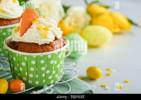 Karottenkuchen Cupcakes zu Ostern. Karotten-Cupcakes mit Frischkäse-Frosting dekoriert mit winzigen MarzipanKarotten auf weißem Backgr Stockfoto