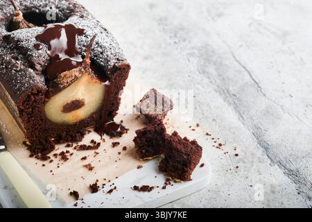 Schokoladenkuchen mit Birnen im Inneren gebacken. Schokolade Birnenkuchen oder dunkle Schokolade Bundt Kuchen mit Birne auf hellgrauem Tisch zu Hause. Stockfoto