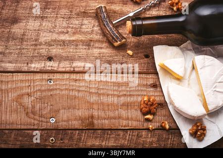Flasche Wein mit Korkenzieher. Mit Trauben, Käse Camembert in Scheiben, Nuss auf altem grauen Betontischhintergrund mit Kopierraum. Rot Stockfoto