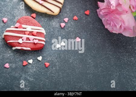 Kekse zum Valentinstag. Shortbread Kekse in süßem rotem Herz mit Schokoladenglasur auf rosa Platte auf grauem Hintergrund. Mütter Stockfoto
