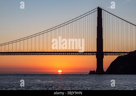 Die Golden Gate Bridge steht vor dem Sonnenuntergang, ihre ikonische Struktur ist ein Zeugnis für ein technisches Wunder, während die Sonne unter dem Horizont eintaucht und den Himmel mit Orange- und Goldtönen bemalt und eine atemberaubende Szene schafft, die die Schönheit und Pracht von San Francisco einfängt. Stockfoto
