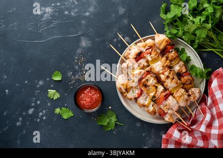 Hähnchenshish Kebab oder Spieße Kebab auf Holzbrett, Gewürze, Kräuter und Gemüse auf dunkelgrauem Hintergrund. Barbecue Rohzutat Stockfoto