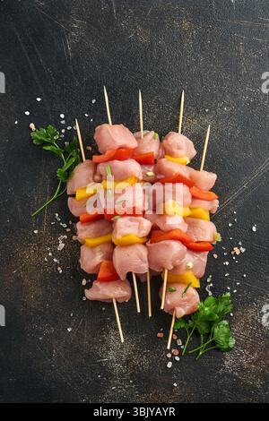 Rohe Stücke Fleisch Zutaten von Huhn auf Holzbrett, Gewürze, Kräuter und Gemüse auf dunkelgrauem Hintergrund. Rohzutaten für Stockfoto