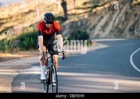 Radfahrer mit Helm und Brille fährt die Straße hinunter Stockfoto