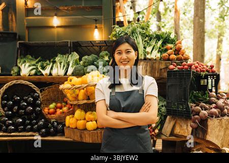 Porträt eines selbstbewussten Außendienstmitarbeiters. Lächelnde Asiatin in einer Schürze, die an ihrem Stand steht. Stockfoto