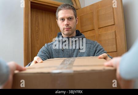 Männlicher Kurier liefert Paket. Paketzustellservice. Stockfoto