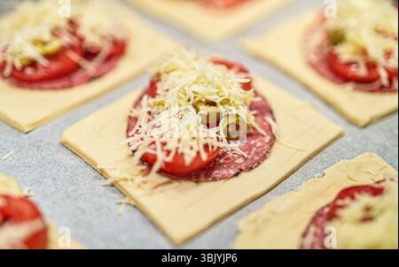 Quadratische Mini-Pizzas mit Salami, Käse, Oliven und Tomaten. Stockfoto