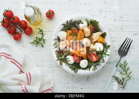 Toskanische Panzanella. Kirschtomaten-Salat mit Rucola, Basilikum, Mozzarella und Brotcrackern auf weißer Schüssel. Traditionelles italienisches s Stockfoto