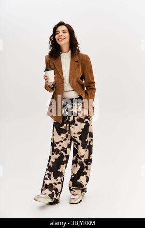 Eine junge, modische Frau posiert selbstbewusst in einem trendigen Outfit mit einer einzigartigen Hose mit Kuhmuster. Stockfoto