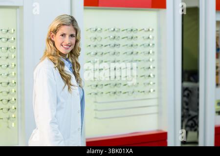 Brillenrahmen für Wandmontage, die auf beleuchteten Tafeln im optischen Einzelhandelsgeschäft mit rotem Regal leuchten Stockfoto