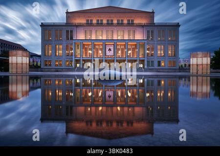 Berühmter Opernsaal in Leipzig Sachsen während der blauen Stunde mit sich bewegenden Wolken, Reflexion im Wasser und einer wunderschönen beleuchteten Fassade Stockfoto