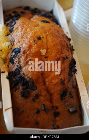 Frisch gebackener Kuchen mit Schokoladenchips in einer Papierform. Goldbraune Kruste, feuchte Textur und hausgemachte Atmosphäre, perfekt für die Dessertszene Stockfoto