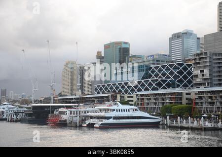 Sydney, New Sowth Wales, Australien. 21. Mai 2013: Sydneys geschäftige Uferpromenade mit Fähren und Wolkenkratzern unter grauem Himmel. Stockfoto