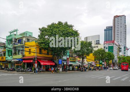 Da Nang, Vietnam - 18. März 2025: Geschäftige urbane Szene in Vietnam mit Straßencafés, farbenfroher Architektur, Motorrädern und großen modernen Hotels Stockfoto
