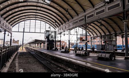 NEWCASTLE, Großbritannien - 13. JUNI 2025 - Passagiere, die unter den Metallbögen des Newcastle Central Station auf den Zug warten Stockfoto